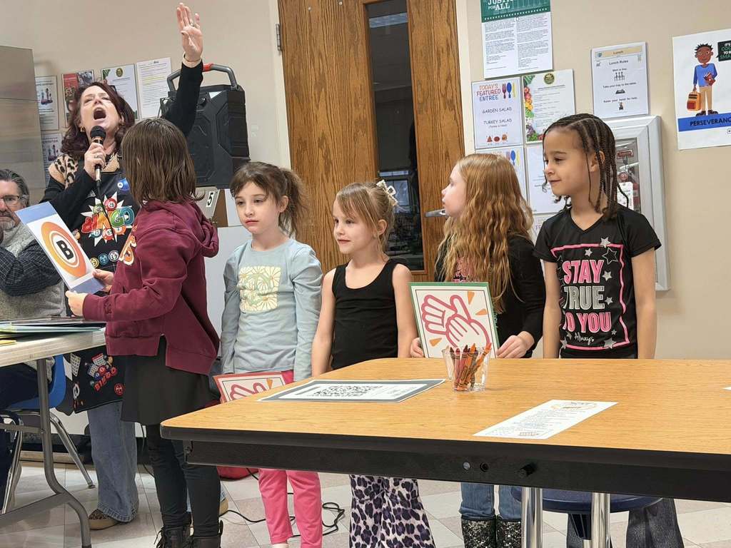 A women singing behind students in a classroom. 