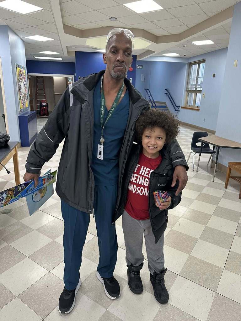 A student smiling next to a man who is wearing blue scrubs. 