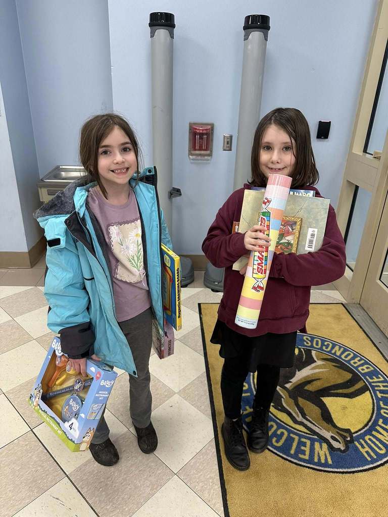 Two students holding treats and games. 
