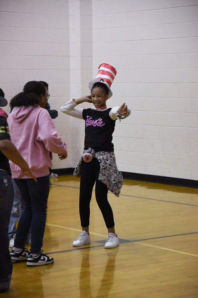 a girl dressed as the cat in the hat dancing in the school gym