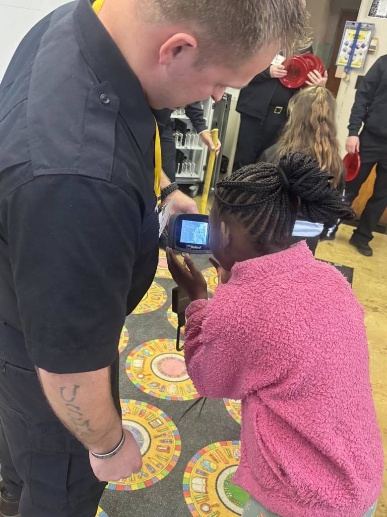 A firefighter showing a student technology they use when on the job. 