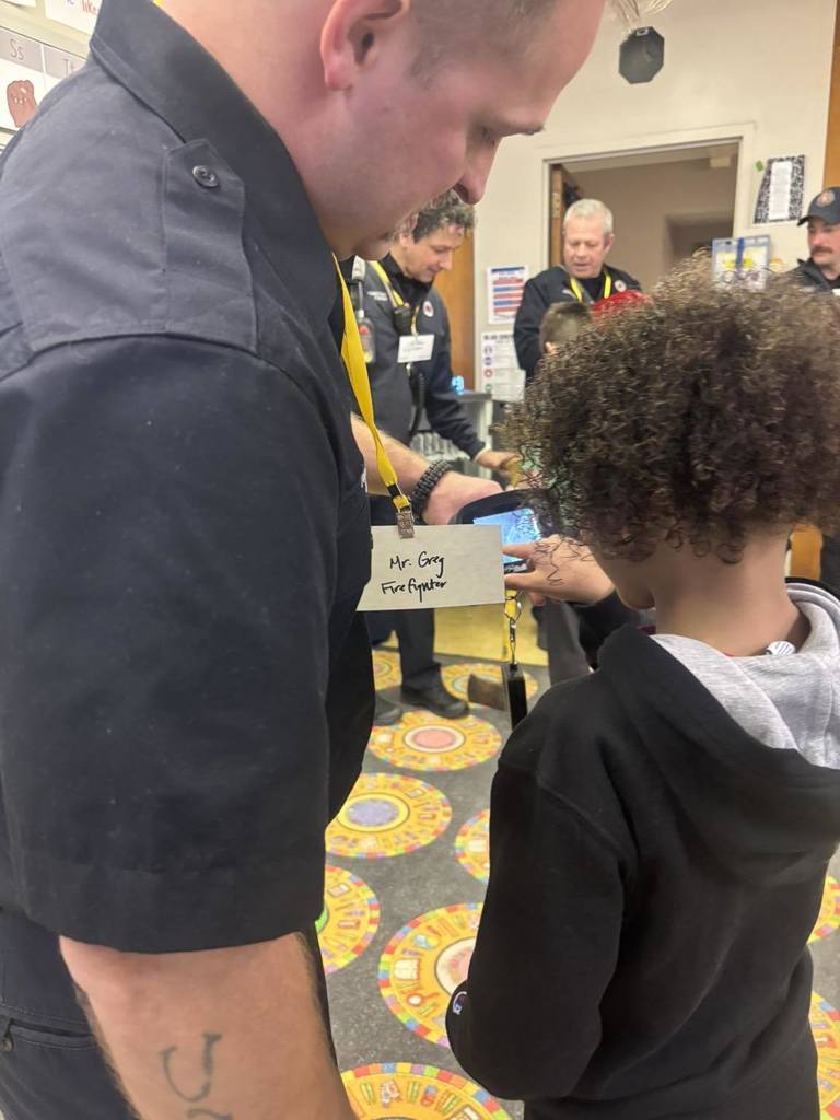 A firefighter showing a student technology they use when on the job. 