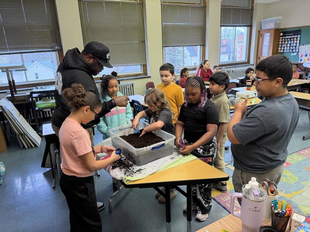 Students playing with dirt and toy cars. 