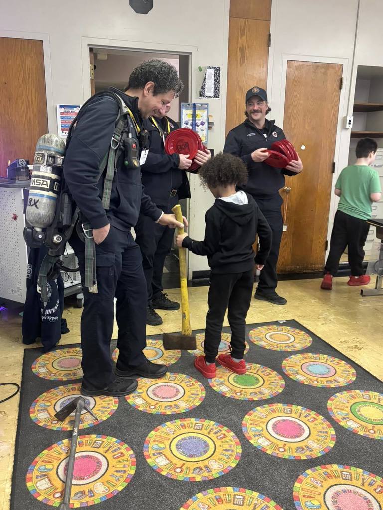 Firefighters showing a student their axe. 