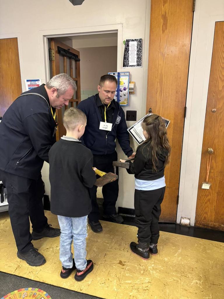 Firefighters showing kids their axes. 