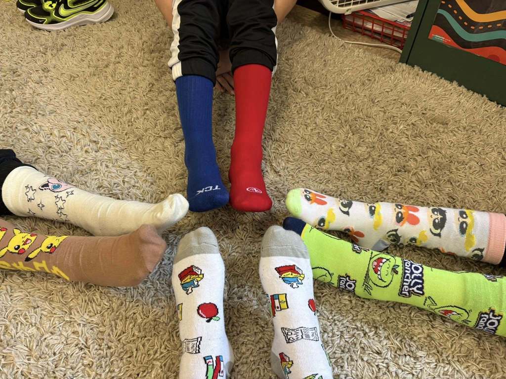 Feet that are wearing crazy and mismatched socks. 