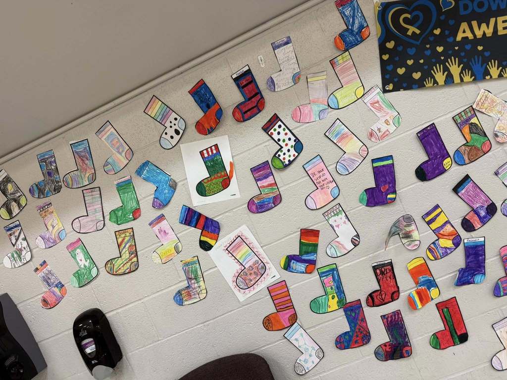 Colorful cut outs of socks that students colored are hanging on the wall. 