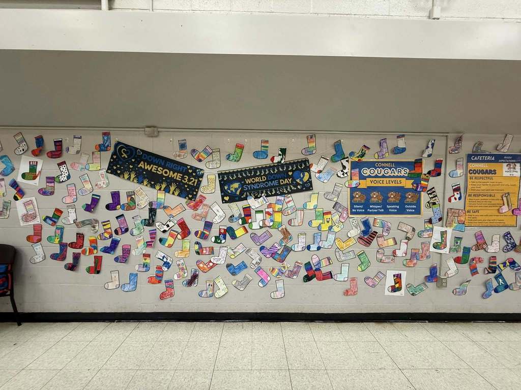 Colorful cut outs of socks that students colored are hanging on the wall. 