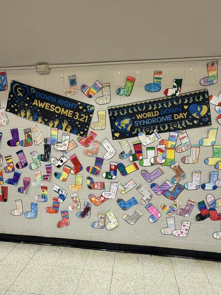 Colorful cut outs of socks that students colored are hanging on the wall. 