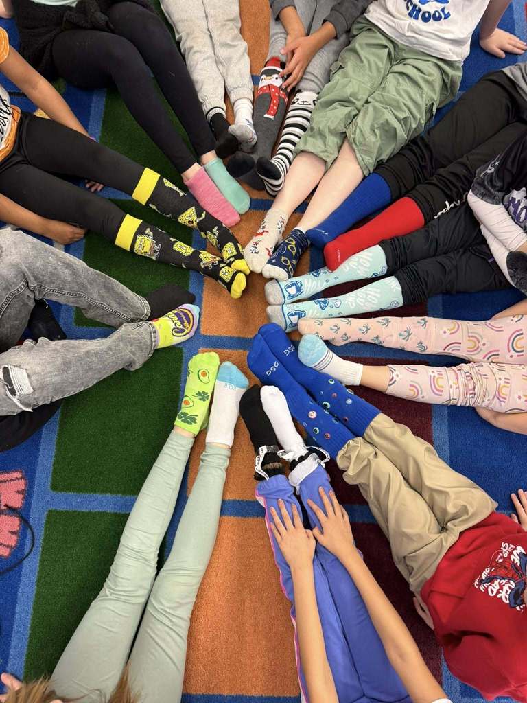 Feet that are wearing crazy and mismatched socks. 