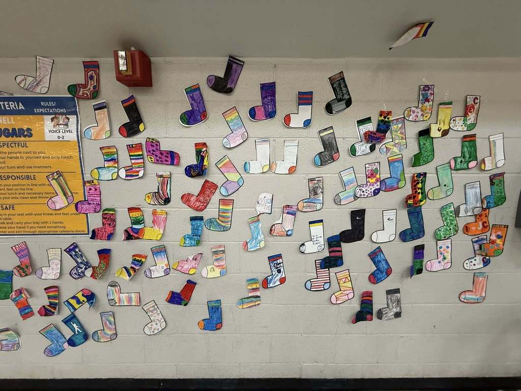 Colorful cut outs of socks that students colored are hanging on the wall. 