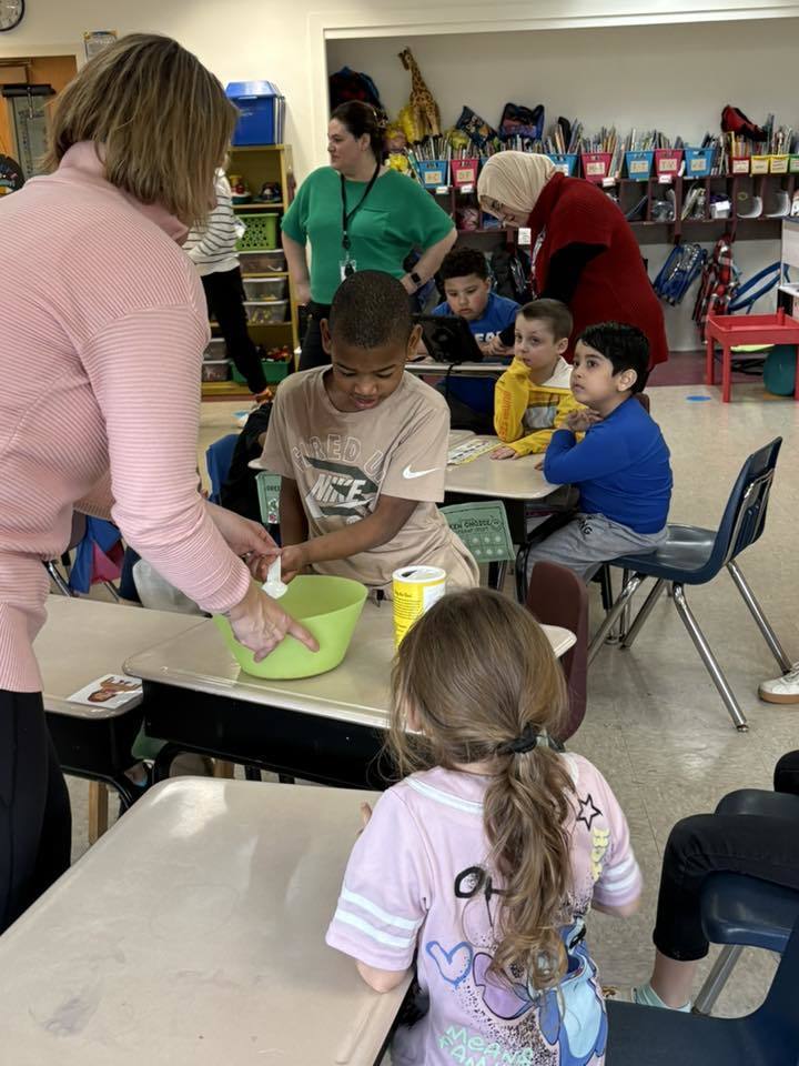 A teacher helping her students prepare to make popcorn. 