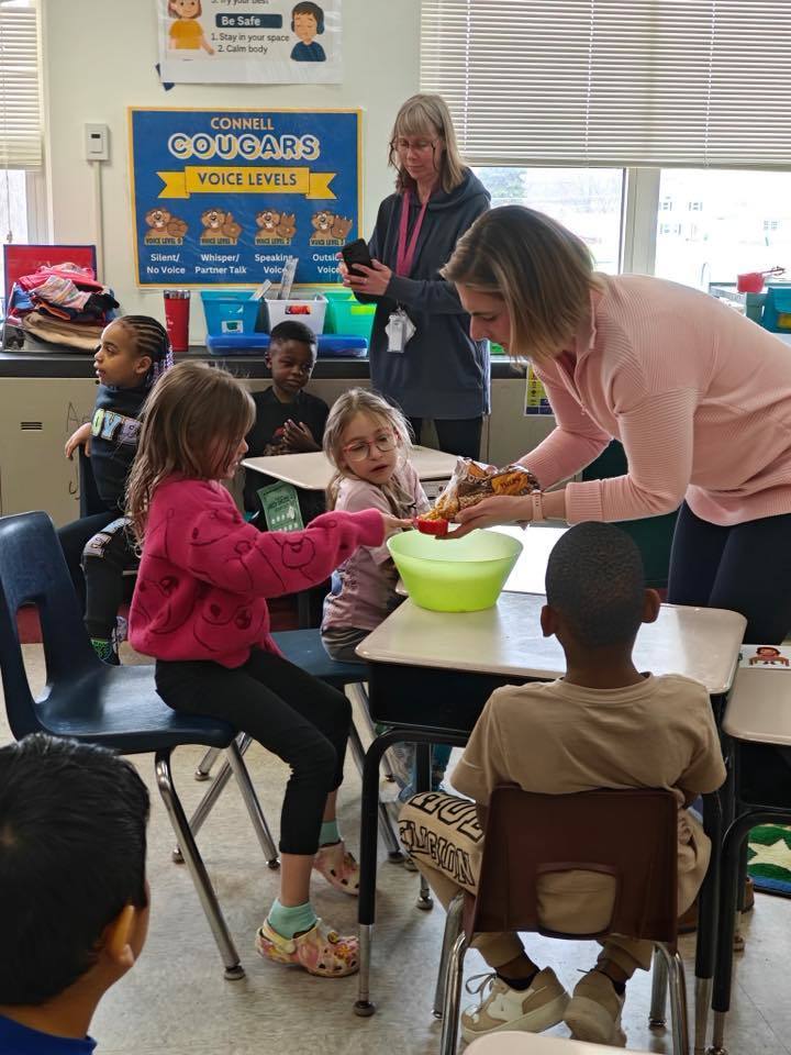 A teacher helping her students prepare to make popcorn. 