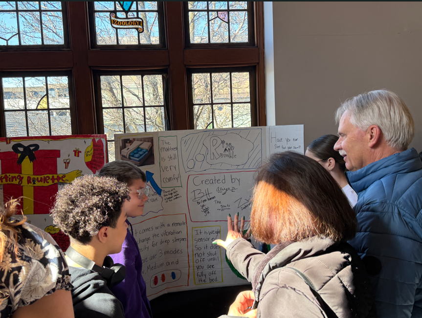 People standing next to tables with tri-folds on them. 