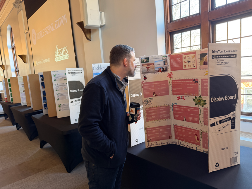 School Board President Dr. Jay Breneman is looking at the tri-fold projects students made. 