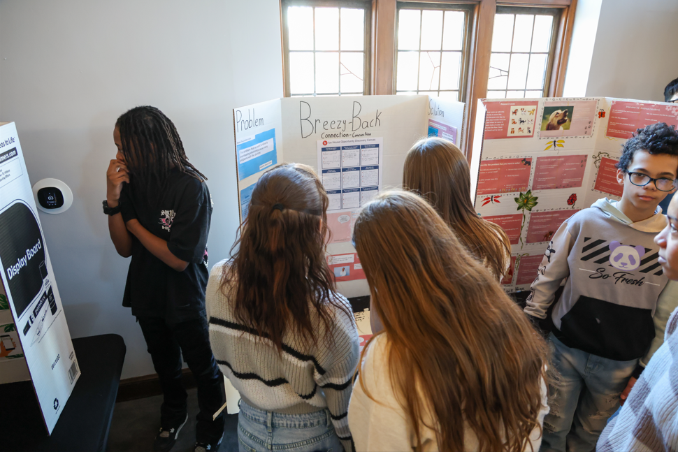 Students are looking at a tri-fold project.