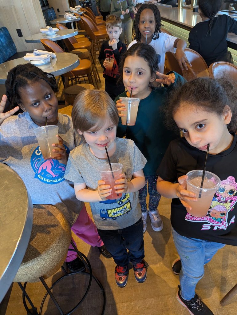 Students standing and drinking their juice from straws. 