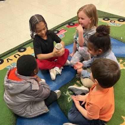 Kids shaking the ingredients in a mason jar to make butter. 