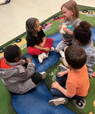 Kids shaking the ingredients in a mason jar to make butter. 