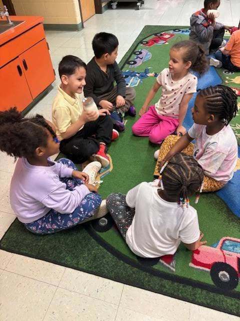Kids shaking the ingredients in a mason jar to make butter. 