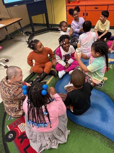 Kids shaking the ingredients in a mason jar to make butter. 