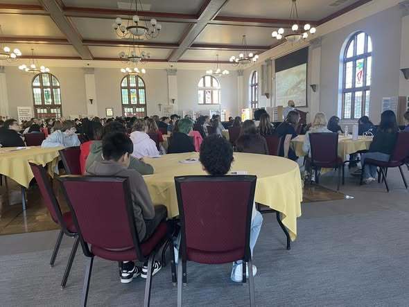 Students sitting at circle tables in a large room. 