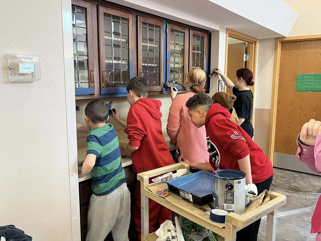 Students paint a brown cabinet to now be blue. 