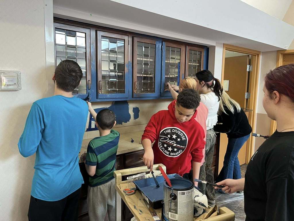 Students paint a brown cabinet to now be blue. 