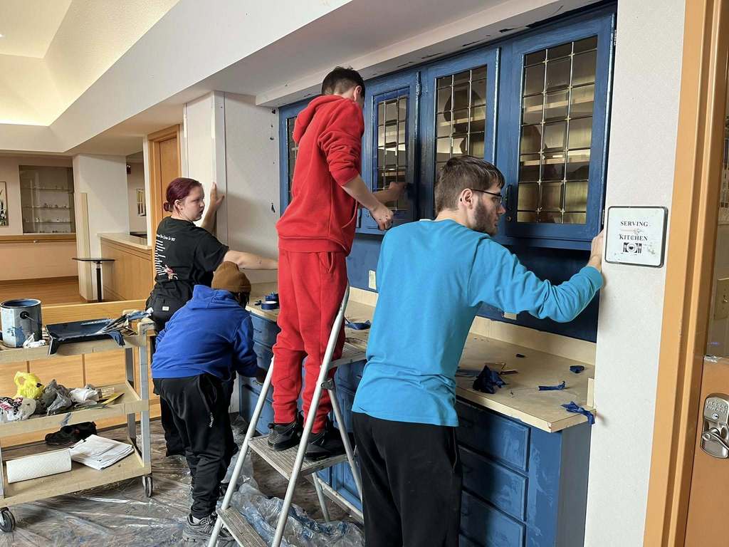 Students paint a brown cabinet to now be blue. 