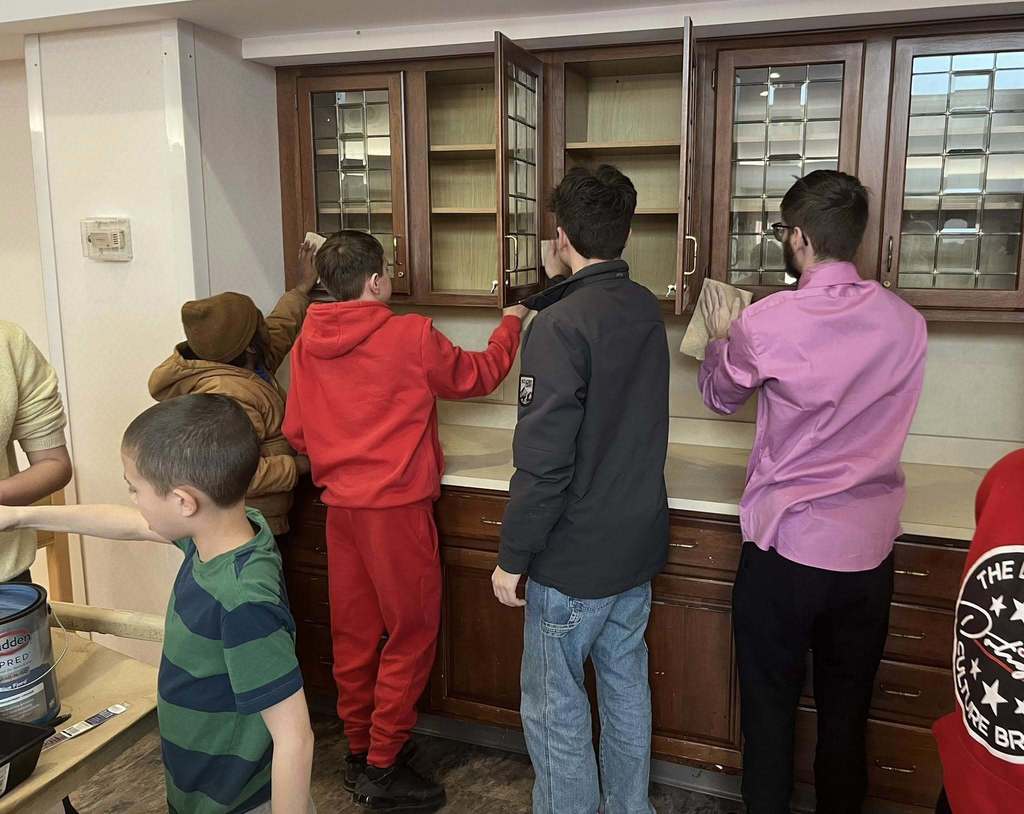 Students prepping a cabinet so they can paint it. 