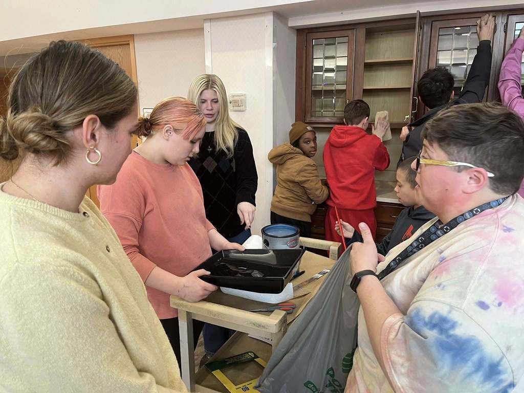 Students prepping a cabinet so they can paint it. 
