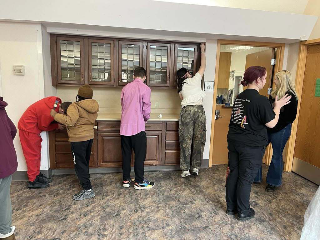 Students prepping a cabinet so they can paint it. 