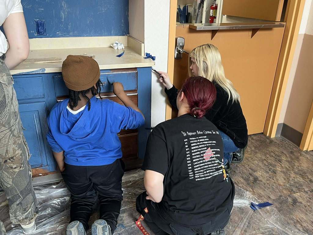 Students paint a brown cabinet to now be blue. 