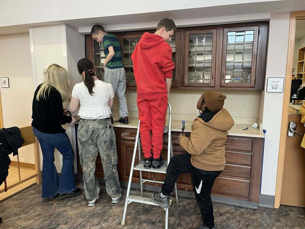 Students prepping a cabinet so they can paint it. 