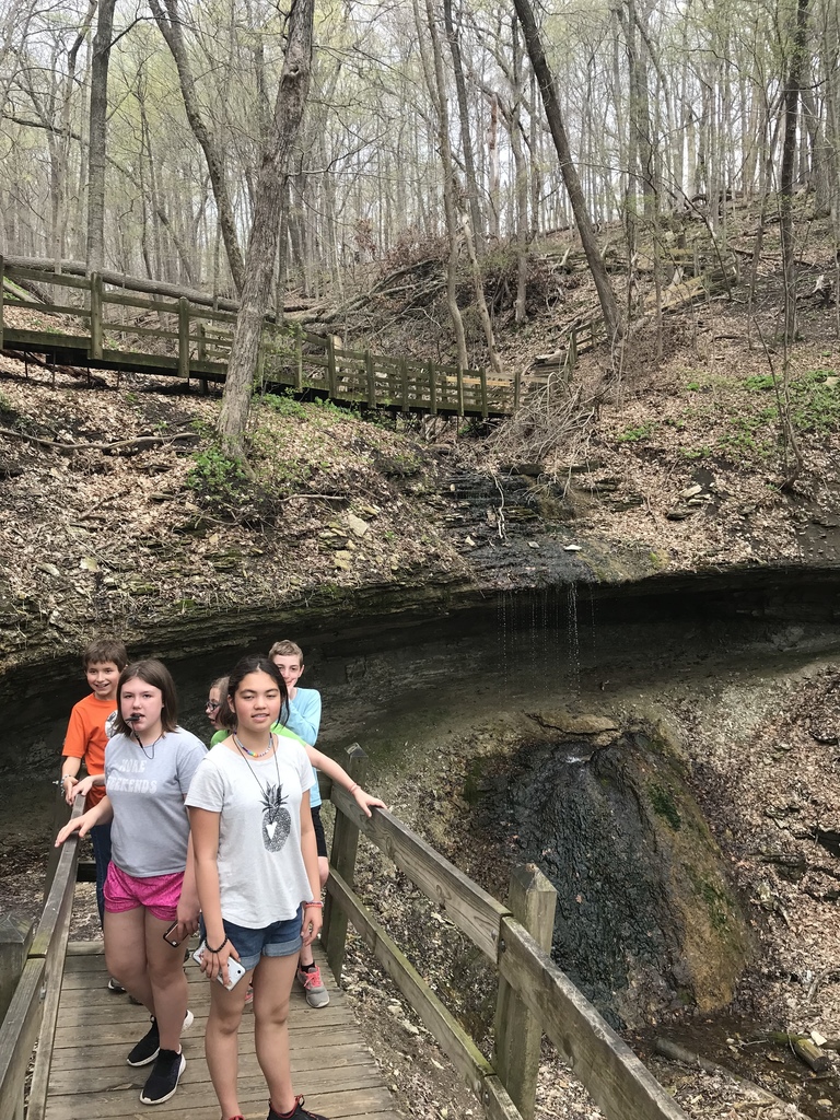students on a hike on a wooden trail bridge with rock formations all around