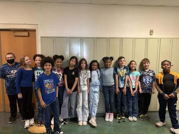 Students wearing blue in front of lockers and posing. 