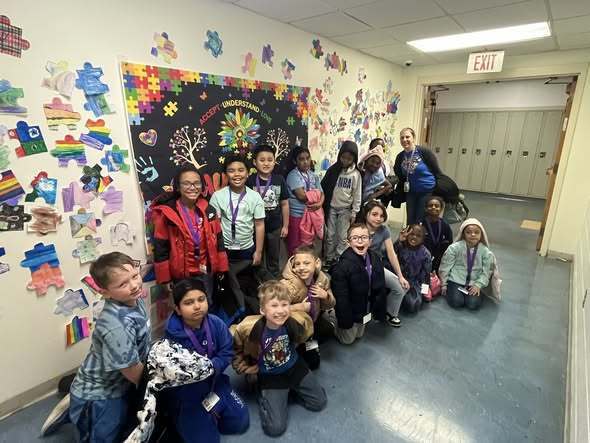 Students wearing blue in a hall and posing. 