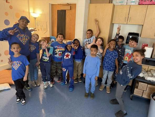 Students wearing blue in a classroom and posing. 
