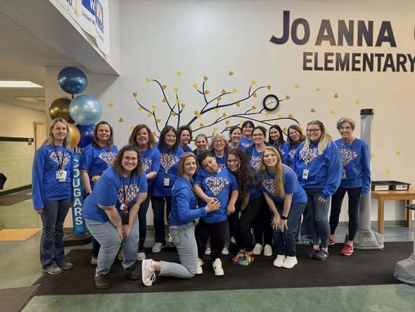Students and staff wearing blue in the hall at JoAnna Connell Elementary School and they are  posing. 