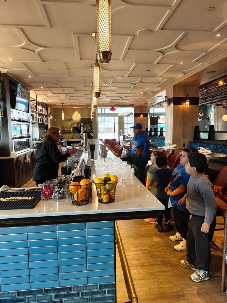 Kids standing in front of a bar top in a restaurant. 