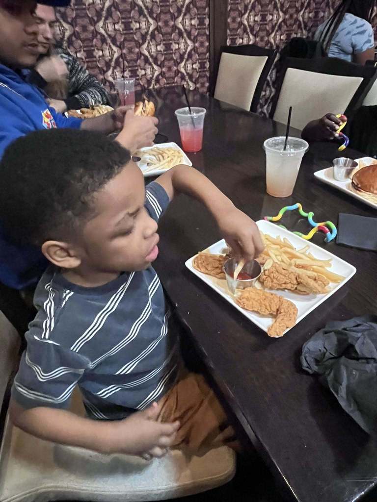 A student eating chicken tenders and fried. 
