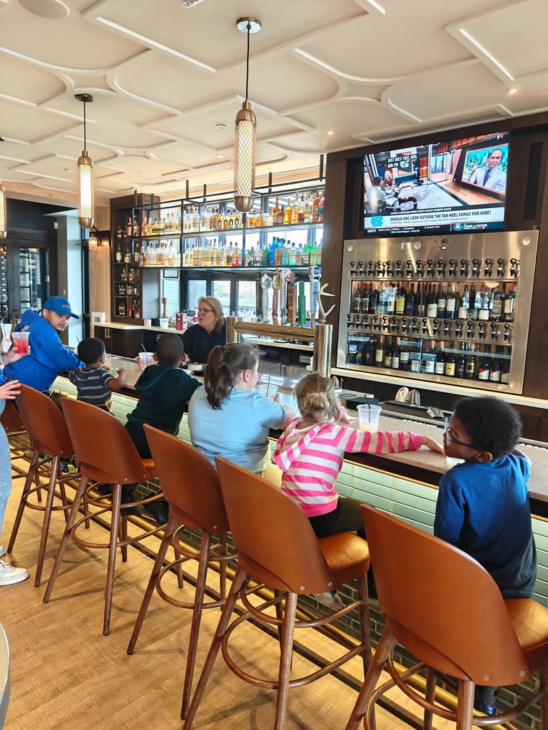 Students and staff sitting at a bar top in a restaurant. 