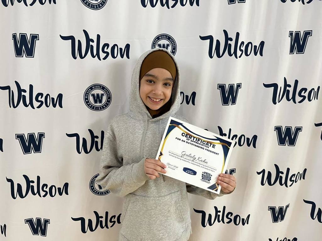 A student in a gray hoodieis holding their certificate. 