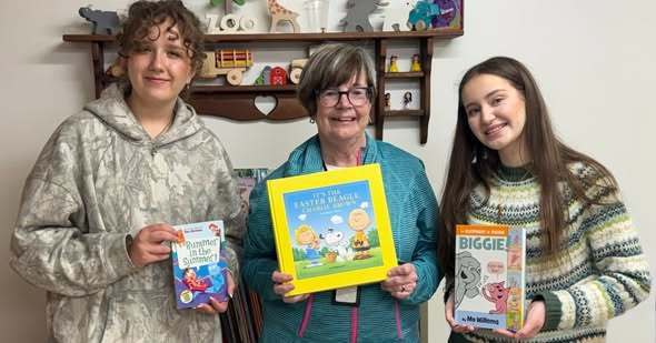 An adult and students holding books. 