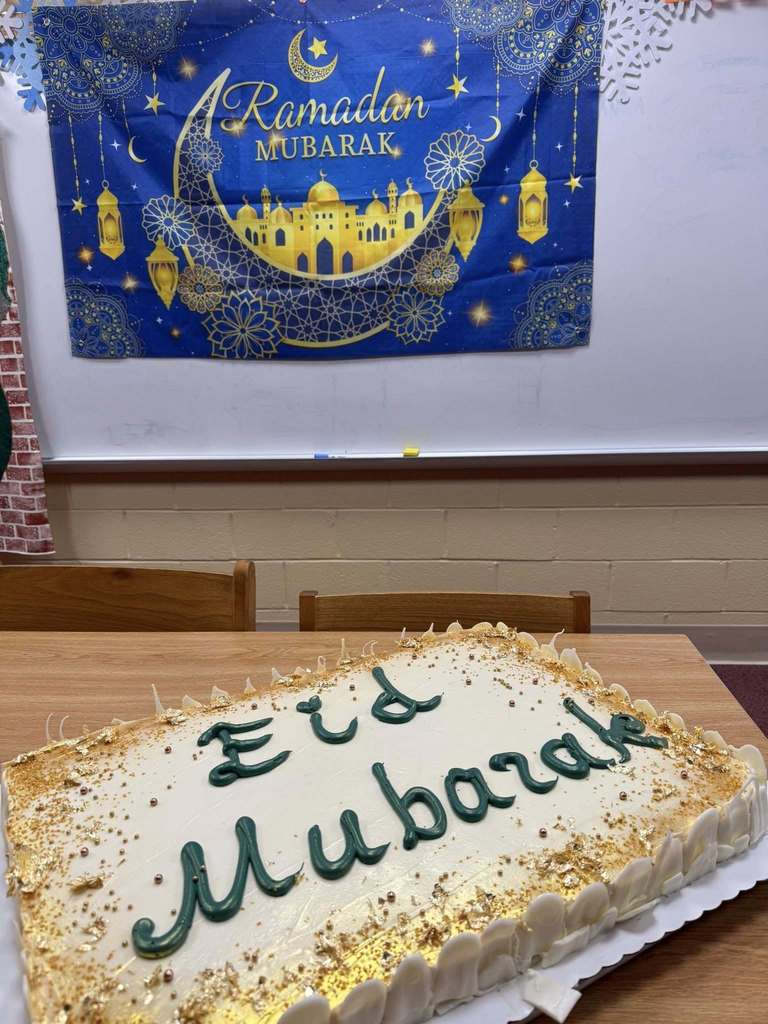 A cake that says Eid Mubarek on it and a Ramadan Mubarek Banner in the back. 