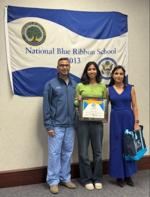 Young girl holding her award and standing next to her parents. 