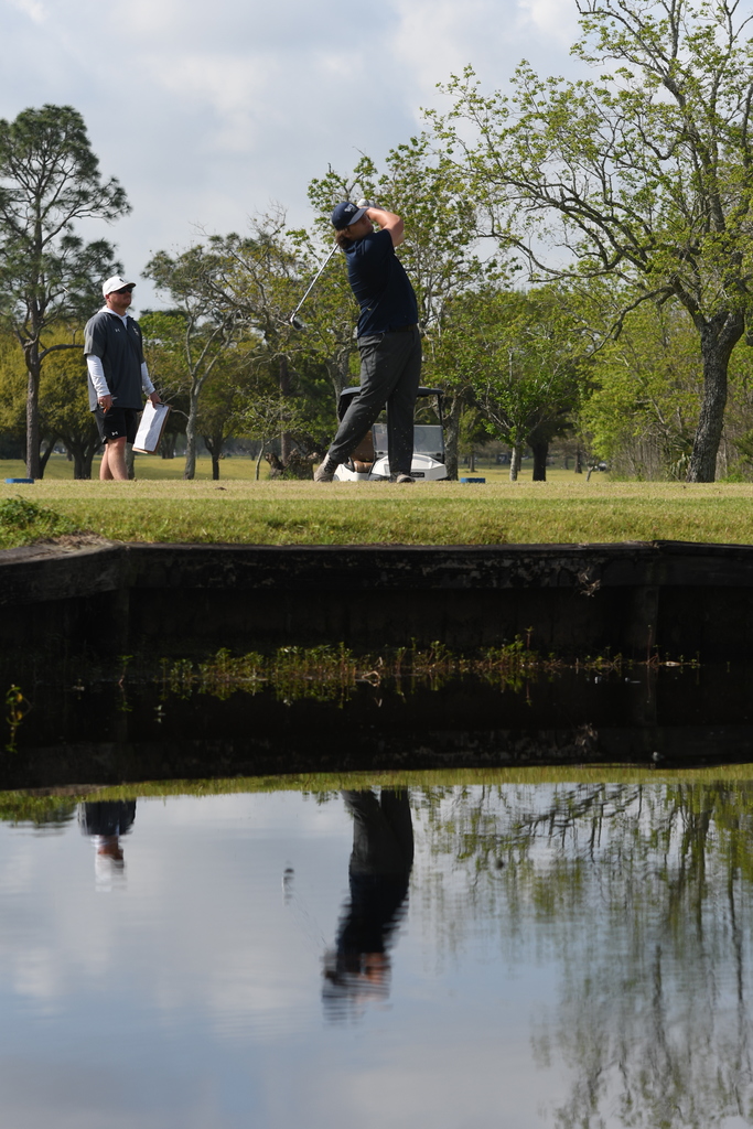 William Pugh swinging a golf club reflected in the water