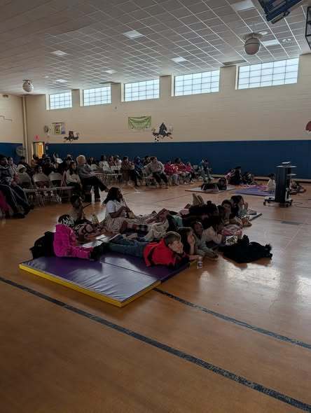 Students sitting on chairs and laying on mats are watching movie.