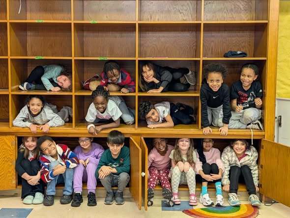 Students curled up in cubbies and smiling.