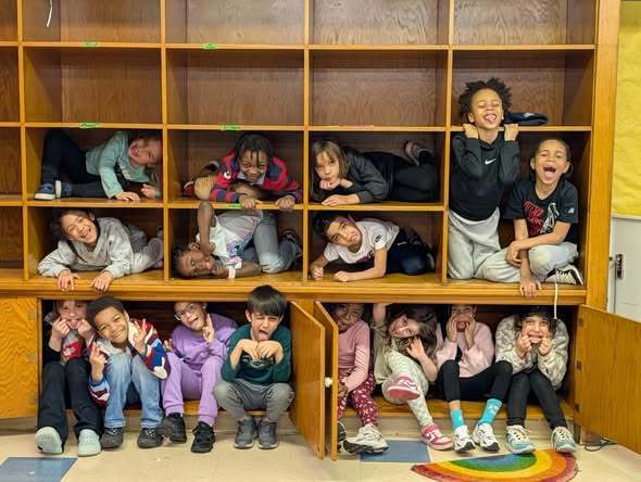 Students curled up in cubbies and smiling.